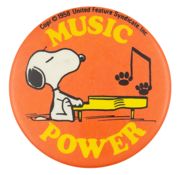 Button displaying yellow text that says 'MUSIC POWER' around an illustration of Snoopy playing a yellow piano on a red-orange background